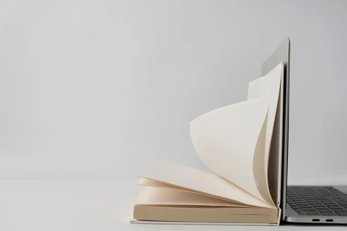 Anordnung mit Laptop und aufgeschlagenem Buch